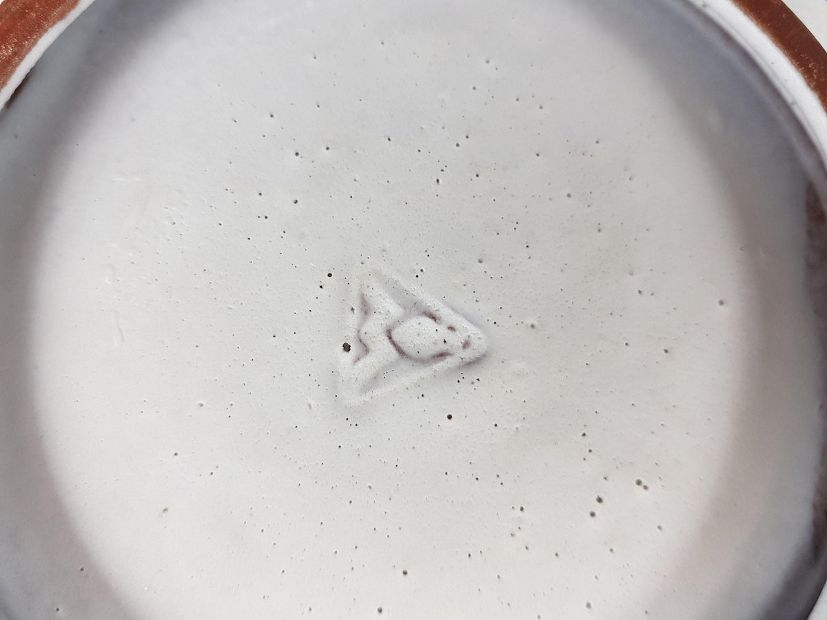 a close-up view of a white surface with a small, circular object in the center, which appears to be a logo or symbol.