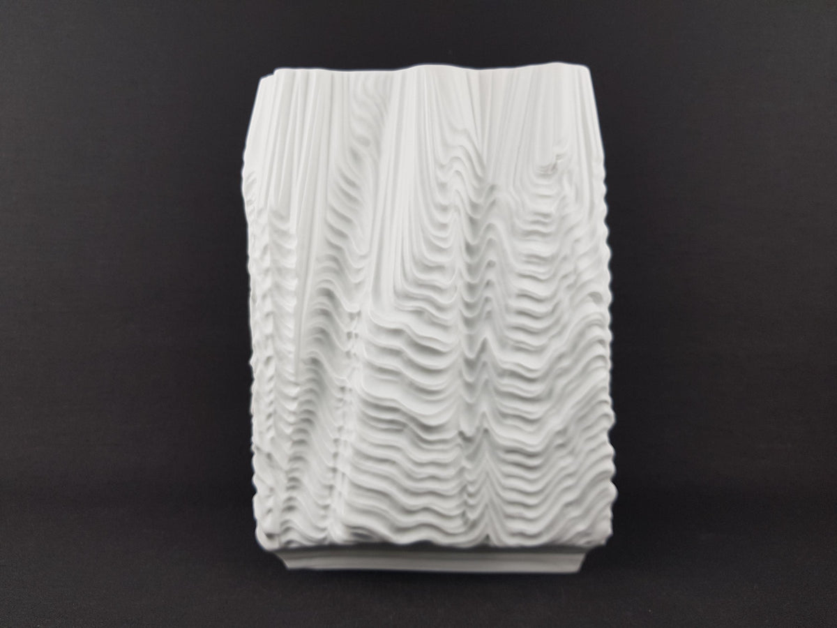 A white, textured ceramic object with a wavy, organic pattern.