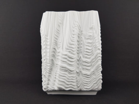 A white, textured ceramic object with a wavy, organic pattern.