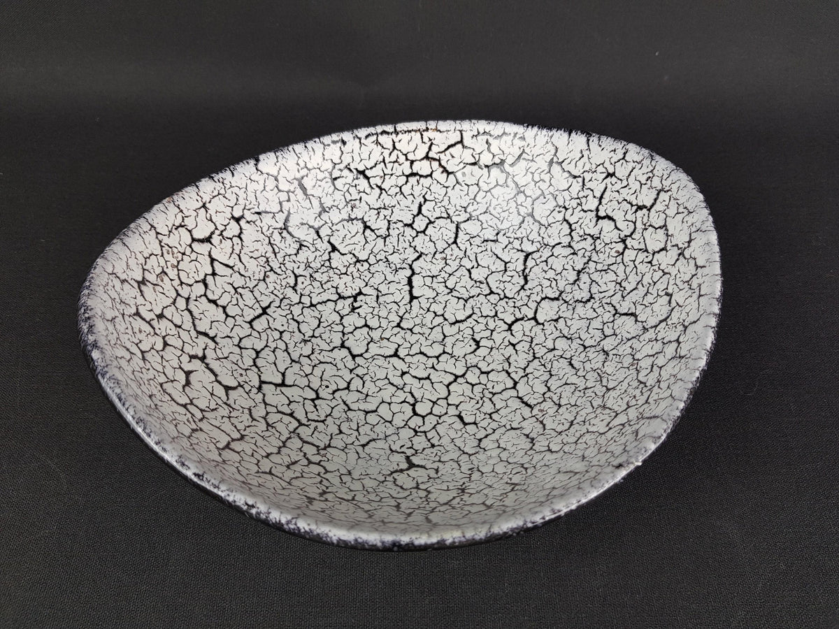 A white ceramic bowl with a cracked and speckled texture, set against a dark background.