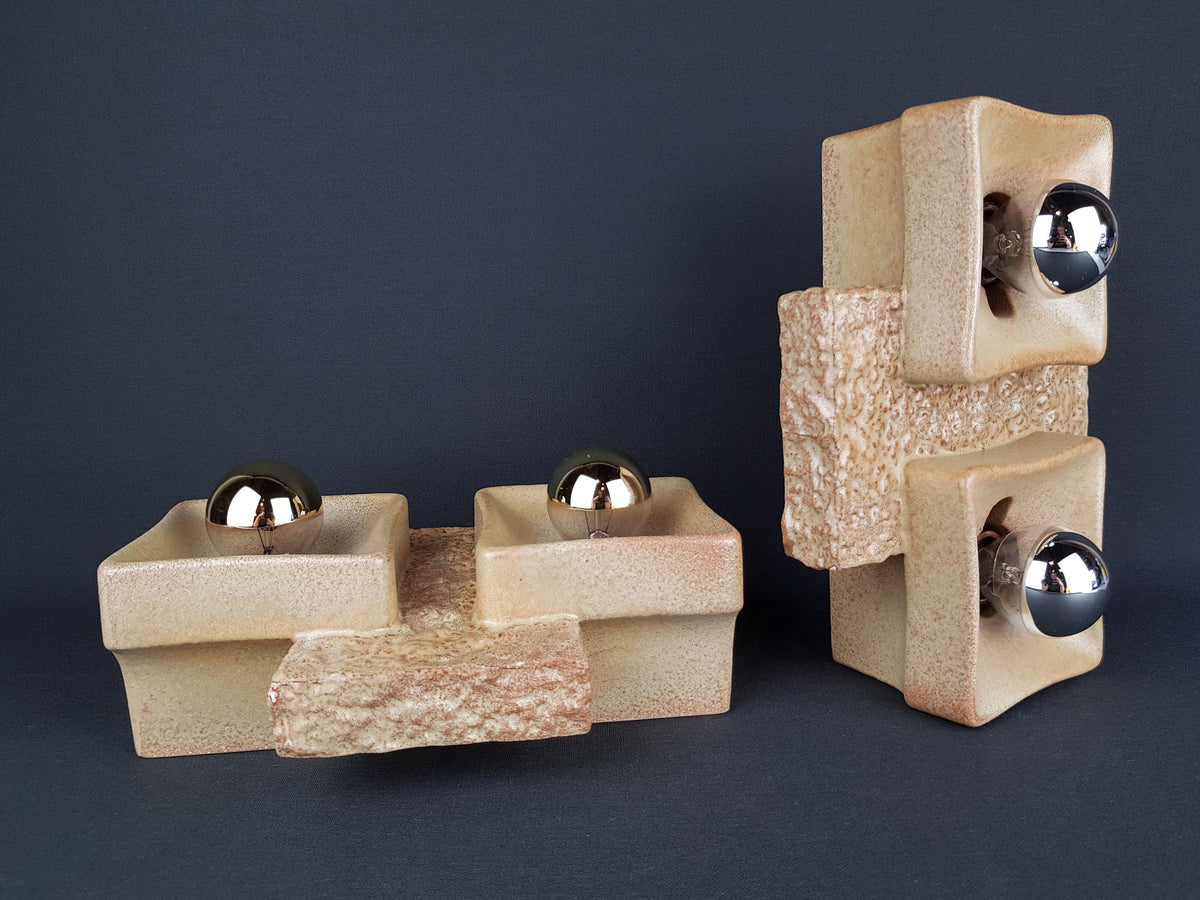 two ceramic sculptures with a geometric design, set against a dark background.