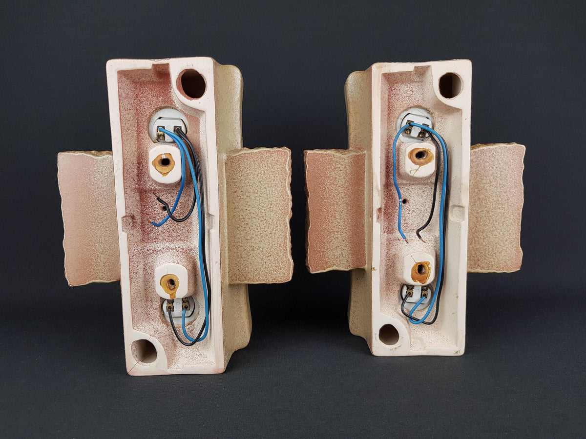 two light fixtures with wires attached to them, placed side by side against a dark background.