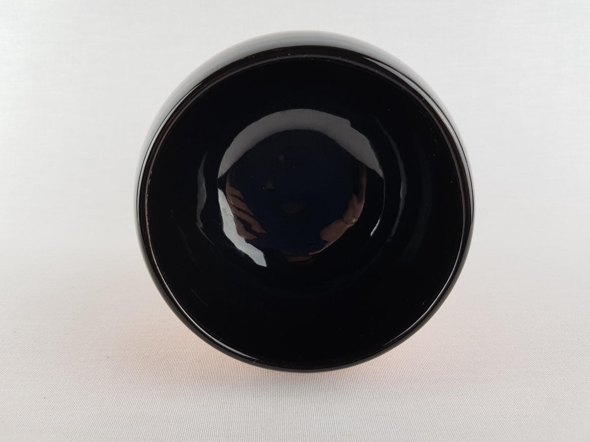 A black bowl with a shiny surface, placed on a plain white background.