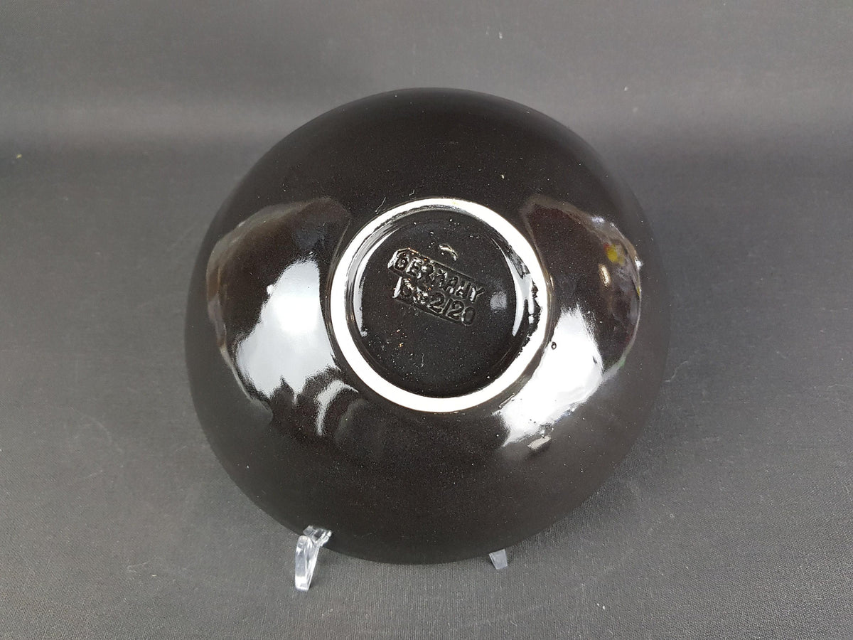 A black ceramic bowl with a white rim, sitting on a gray surface.
