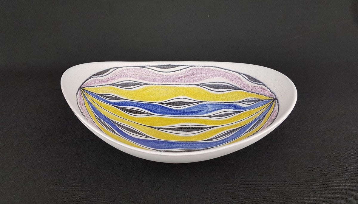 A white bowl with a colorful, abstract design featuring yellow, blue, and purple lines and shapes.